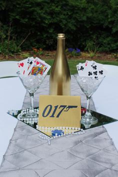 a table topped with two wine glasses filled with playing cards and a bottle of champagne