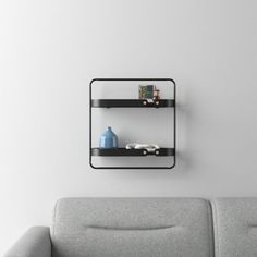 two black shelves on the wall above a gray couch