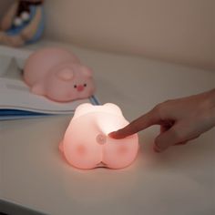 a person pointing at a pink light on a white table with other items in the background