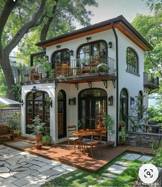 a white house with lots of windows and balconies on the second floor, surrounded by greenery