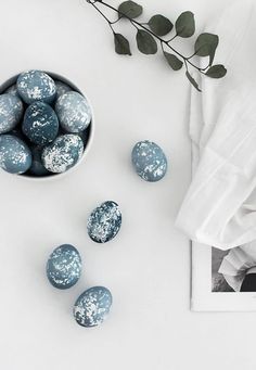 blue and white painted eggs in a bowl next to an image of a plant on a table