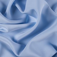 a close up shot of a light blue satin fabric with very soft folds on it