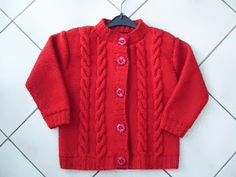 a red sweater with buttons on the collar is laying on a tile floor next to a black hanger