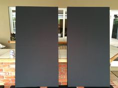 two black speakers sitting next to each other in front of a brick wall and floor