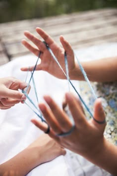 two women are doing something with yarn on their hands and one woman is holding the string