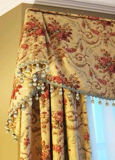 the curtains are hanging in front of the window with beading on them and flowers