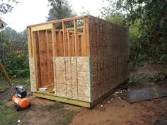 a small shed is being built in the woods with wood framing on it's sides