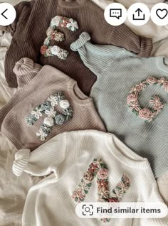 four sweaters with flowers on them laying on a bed