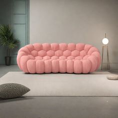 a pink couch sitting on top of a white rug next to a lamp and pillow