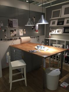 a kitchen with a wooden table surrounded by white chairs