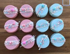 some pink and blue cupcakes with beaded hair clips on them sitting on a wooden table