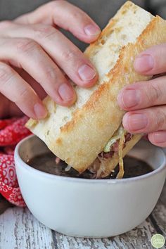 a person is holding a sandwich over a bowl of chocolate sauce and dipping it into the dip