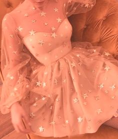 a woman sitting on a couch wearing a dress with white stars all over it,