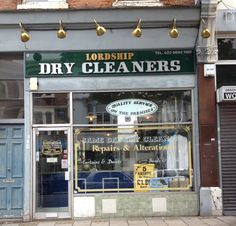 a store front with dry cleaner's on the outside and gold lights above it