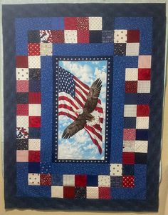 an american flag and eagle quilt hanging on a wall in a room with blue walls