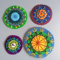 three colorful coasters with designs on them sitting next to each other in front of a white wall