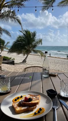 a white plate topped with food on top of a wooden table next to the ocean