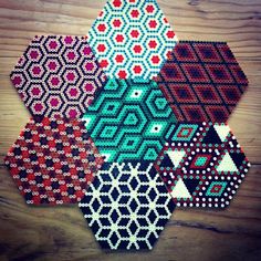 four hexagons made out of beading on a wooden surface with red, green and blue designs