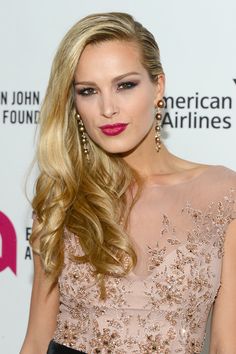 a woman with long blonde hair wearing a pink dress and red lipstick is posing for the camera