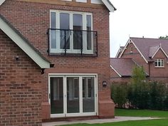 a brick house with an open patio and sliding glass doors on the second story window