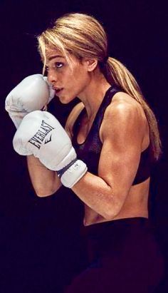 a woman wearing white boxing gloves standing in front of a black background