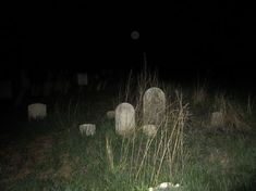 several headstones in the grass at night