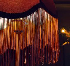 a close up of a lamp with fringes hanging from it's side and a candle in the background