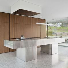 a modern kitchen with stainless steel counter tops and wooden cabinetry, along with an island in the middle