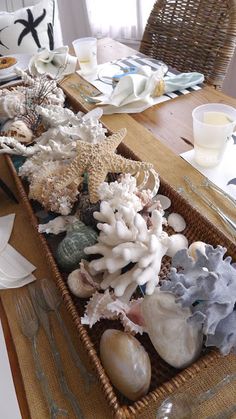 a basket filled with sea shells on top of a table next to plates and utensils