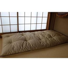 a mattress is placed on the floor in front of an open window with tatami mats