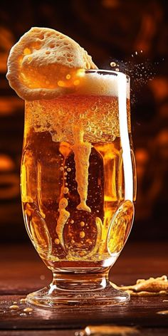 a glass filled with liquid and ice on top of a wooden table next to crackers