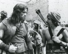 black and white photograph of two men dressed in native american clothing, one holding an arrow