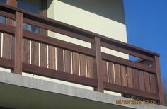 a balcony with wooden railing and balconies on the side of a building against a blue sky