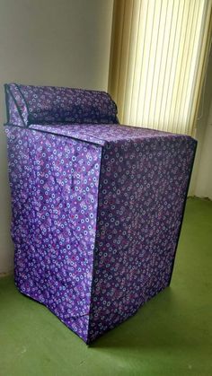 a large purple box sitting on top of a green floor next to a white wall