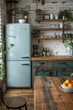 a blue refrigerator sitting in the middle of a kitchen next to a table with oranges on it