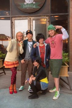 four people posing for a photo in front of a restaurant