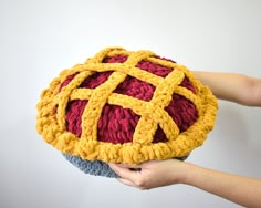 a person holding a crocheted cushion in their hand