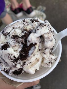 an ice cream sundae in a paper cup with chocolate and white icing on top