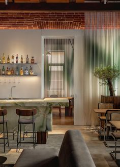 a bar with stools and bottles on the shelves in a room that has brick walls