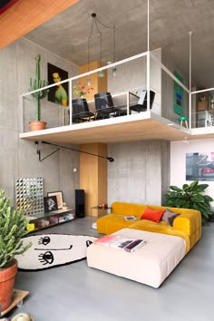 a living room filled with lots of furniture next to a tall white staircase above a yellow couch