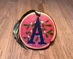 a painted wooden monogrammed ornament with the letter a on it's side