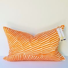 an orange and white striped pillow with a tag on it