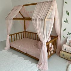 a pink canopy bed in a girls'bedroom with white walls and carpeted flooring