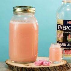 a bottle of pink liquid next to a jar of sugar cubes on a wooden table