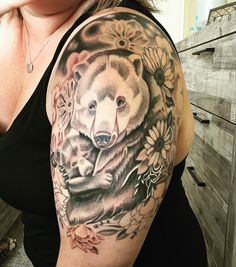 a woman with a bear and flowers tattoo on her arm is posing for the camera