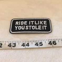 a white and black patch that says ride it like you stole it