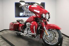 a red motorcycle is on display in a room with black and white checkered flooring