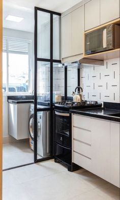 a kitchen with white cabinets and black counter tops next to a washer and dryer