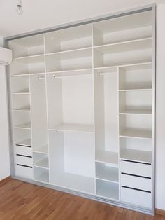 an empty white closet with shelves and drawers on the wall next to a hard wood floor