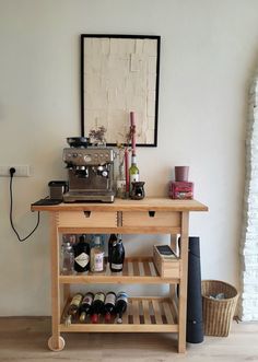 a wooden table topped with bottles of wine next to a shelf filled with bottles and glasses